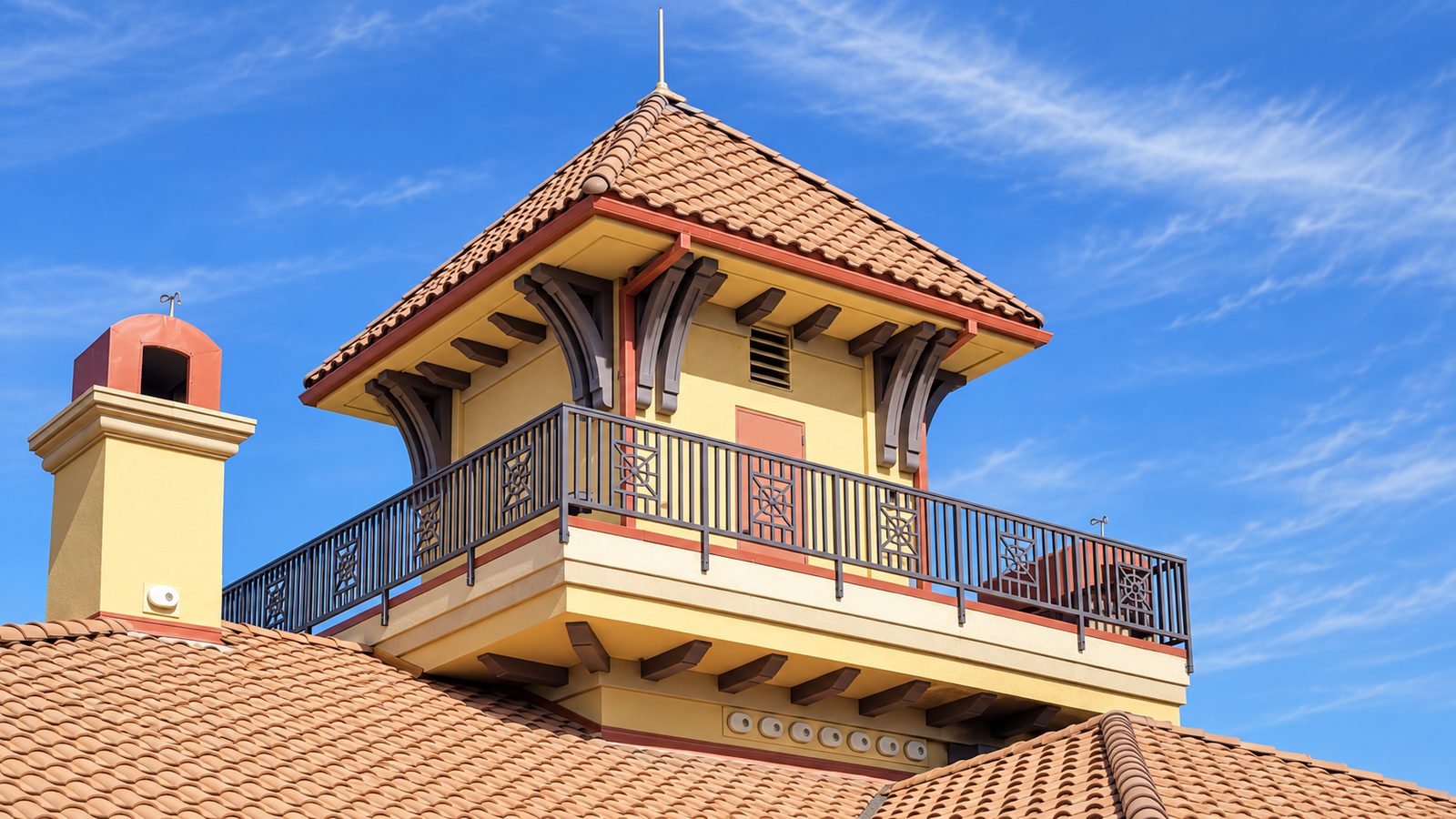 Decorative black guardrail with square starburst panel inserts around a tile-roofed rooftop cupola